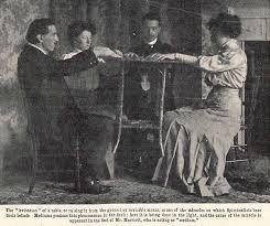 Vintage photograph of a Victorian-era séance with four people levitating a table.